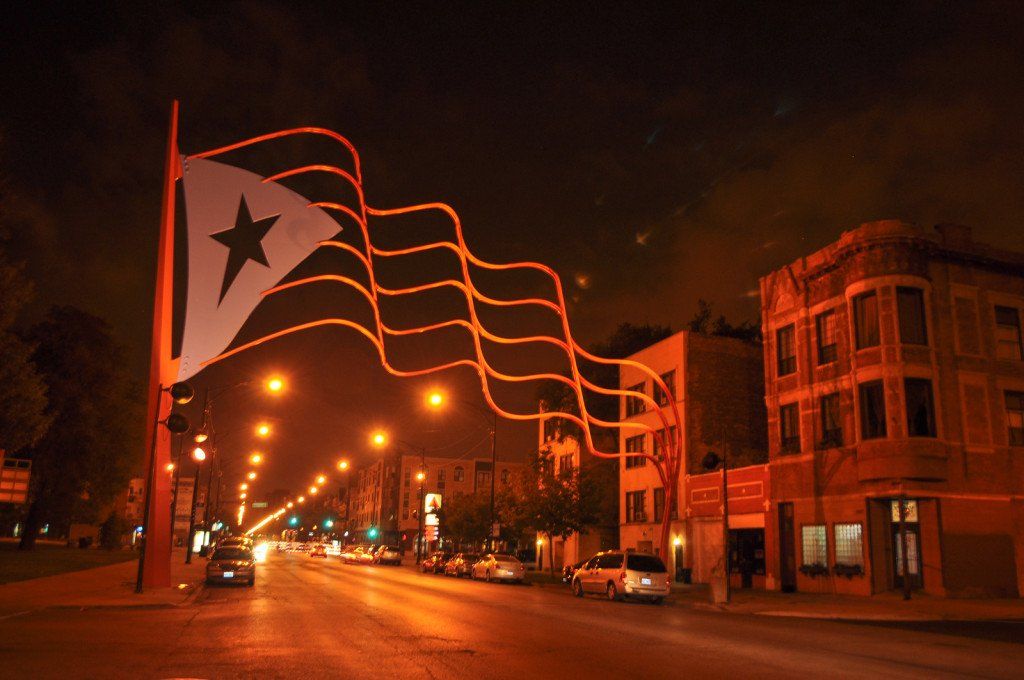 Flag sculpture going over a city street at night