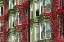 Green apartment building with red fire escapes