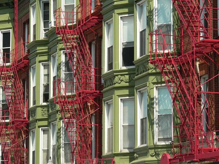 Green apartment building with red fire escapes