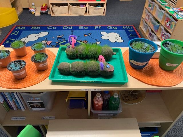 A preschool classroom with play structures, tables, and an alphabet rug.