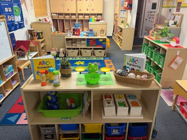 Teacher and child wearing masks use hand sanitizer in a classroom.