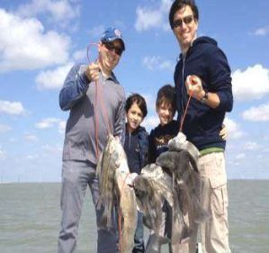 two men and their sons holding fish