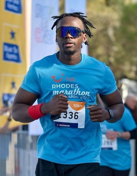 Man running Rhodes Marathon, wearing blue shirt, sunglasses, and bib number 336.