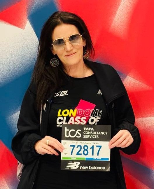 Woman holding a race bib, standing in front of a colorful backdrop.