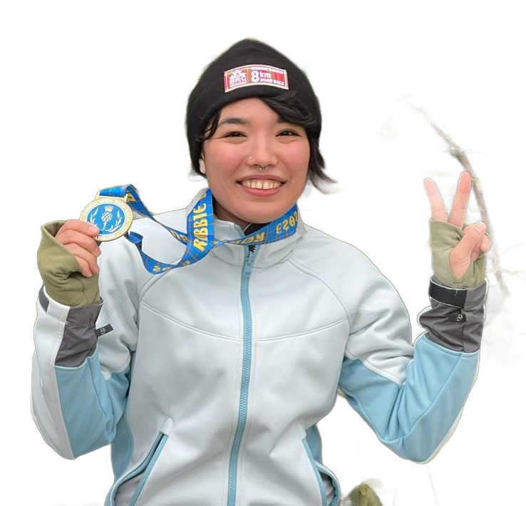 Person in winter gear holds medal, gives peace sign.