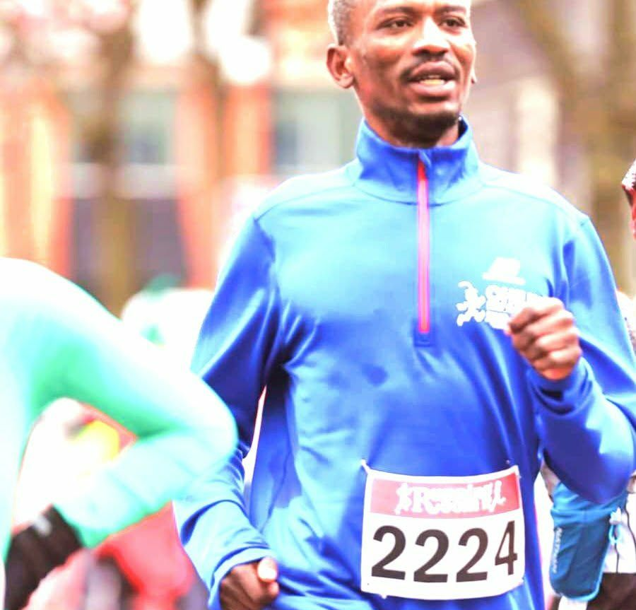 Man running a race, wearing a blue shirt with a pink zipper, bib #2224.