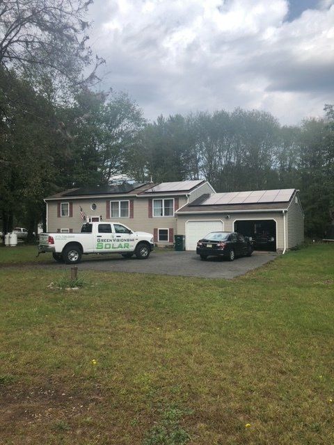 a white truck is parked in front of a house with solar panels on the roof 