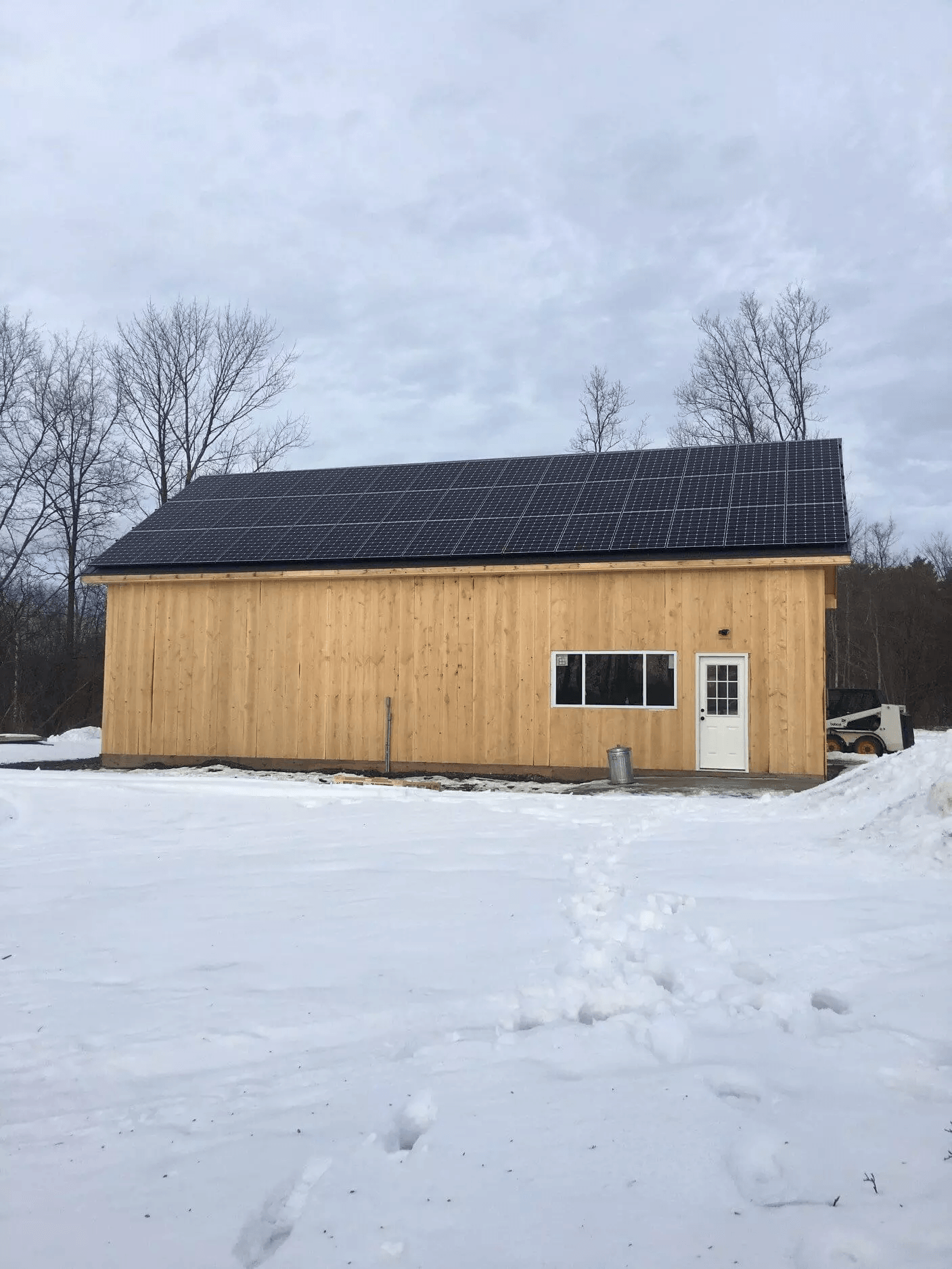 a large wooden building with a black roof is sitting in the middle of a snowy field .