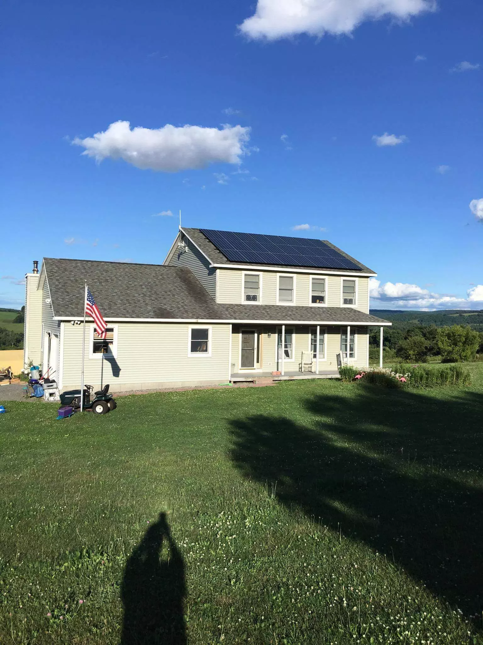a house with solar panels on the roof is sitting on top of a lush green field 