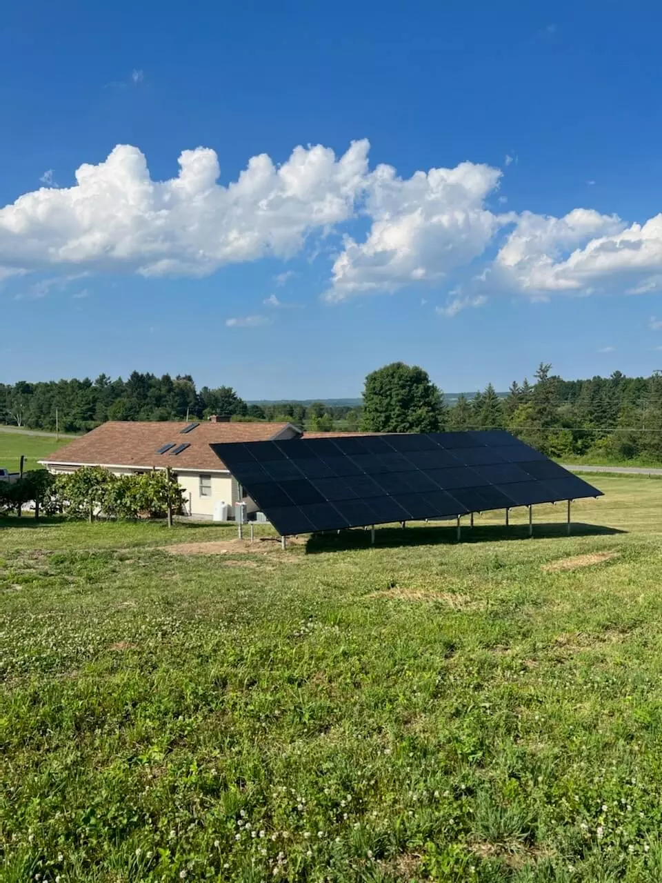 a solar panel is sitting in a grassy field in front of a house
