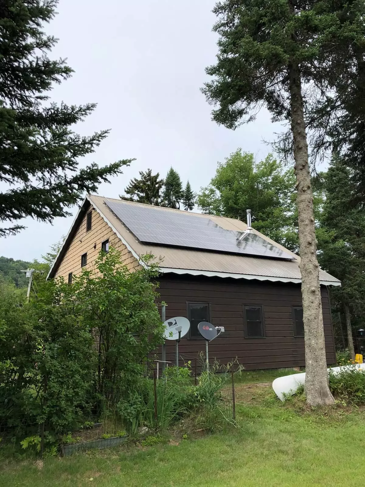 a house with solar panels on the roof is surrounded by trees .