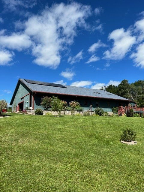 a large green barn is sitting in the middle of a lush green field 