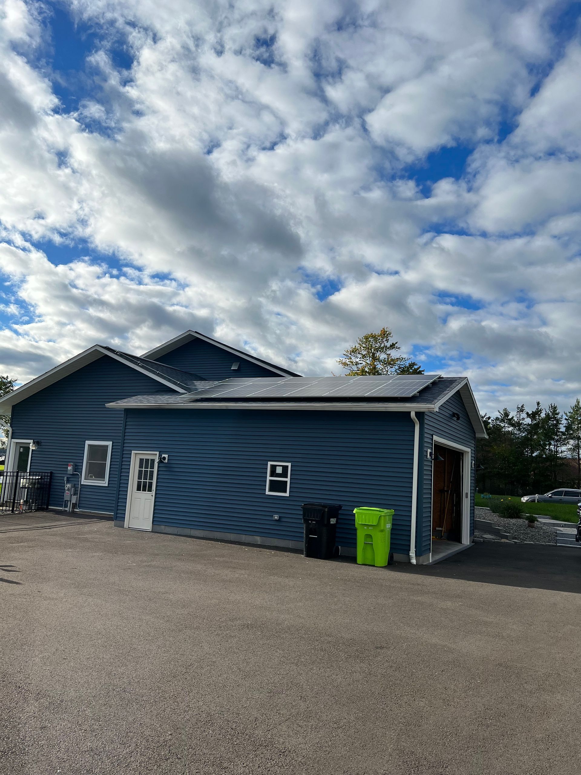 a blue house with a garage and trash cans in front of it 