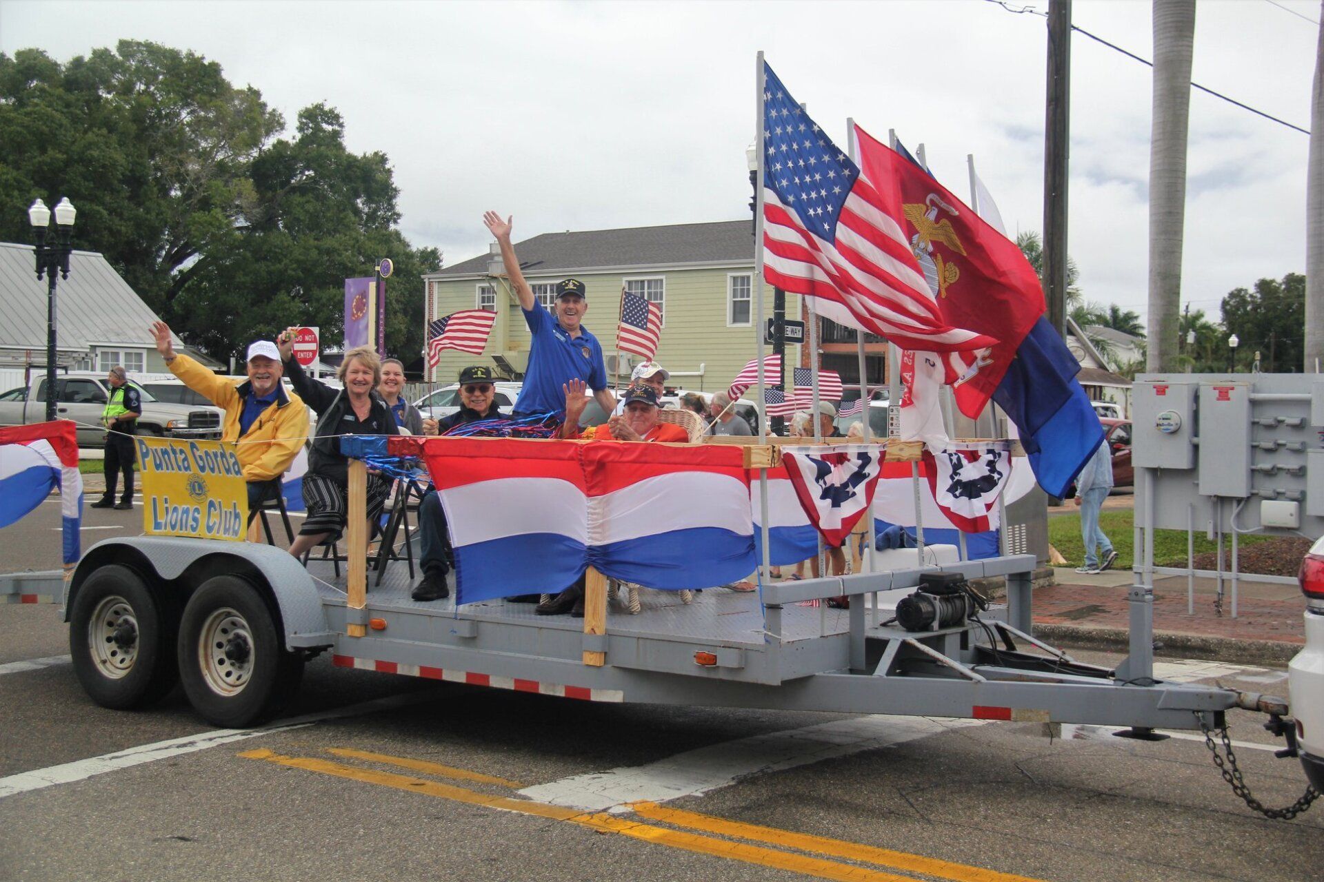 People waving on a trailer decorated with flags and patriotic bunting.