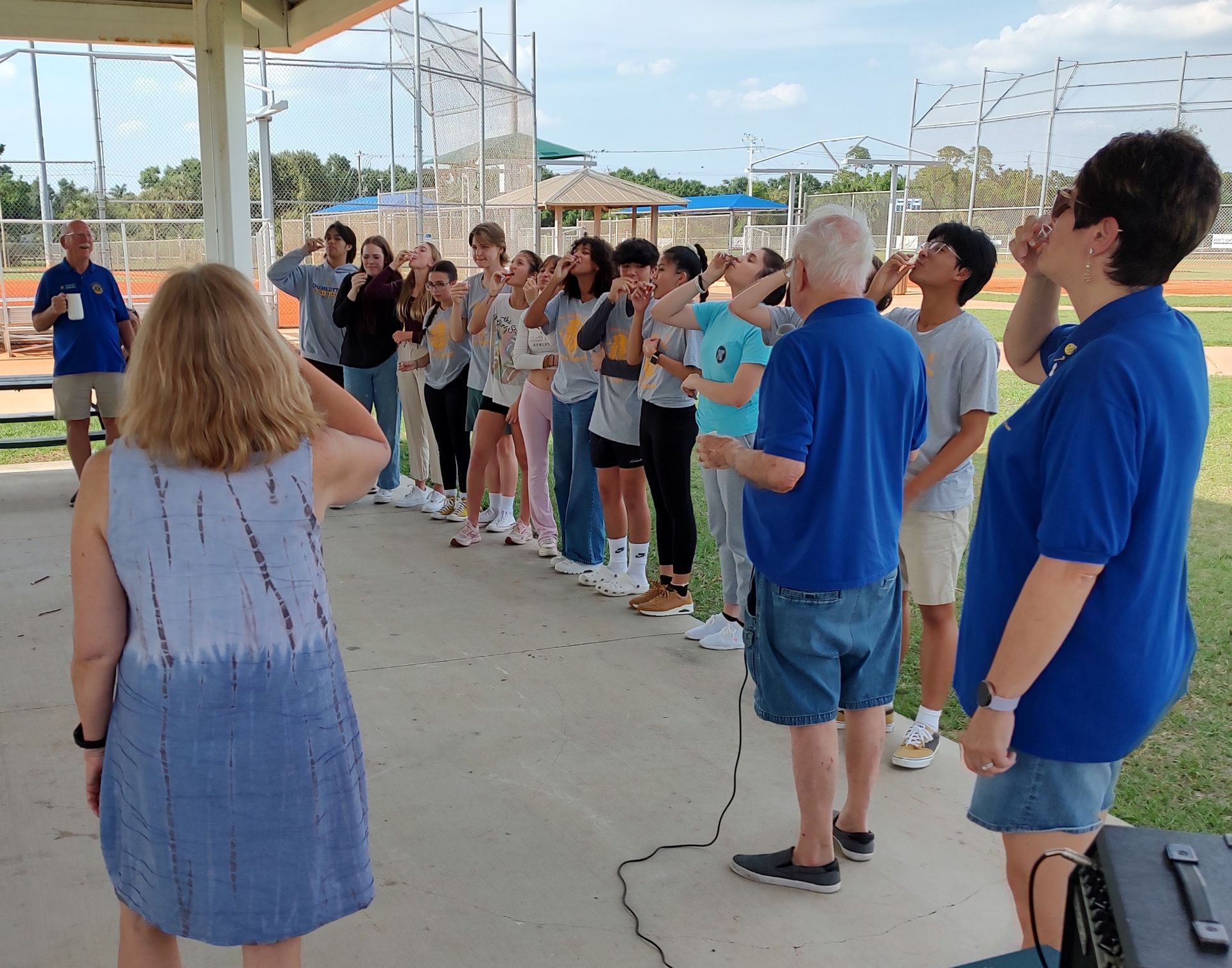 People outdoors raising arms, possibly singing.
