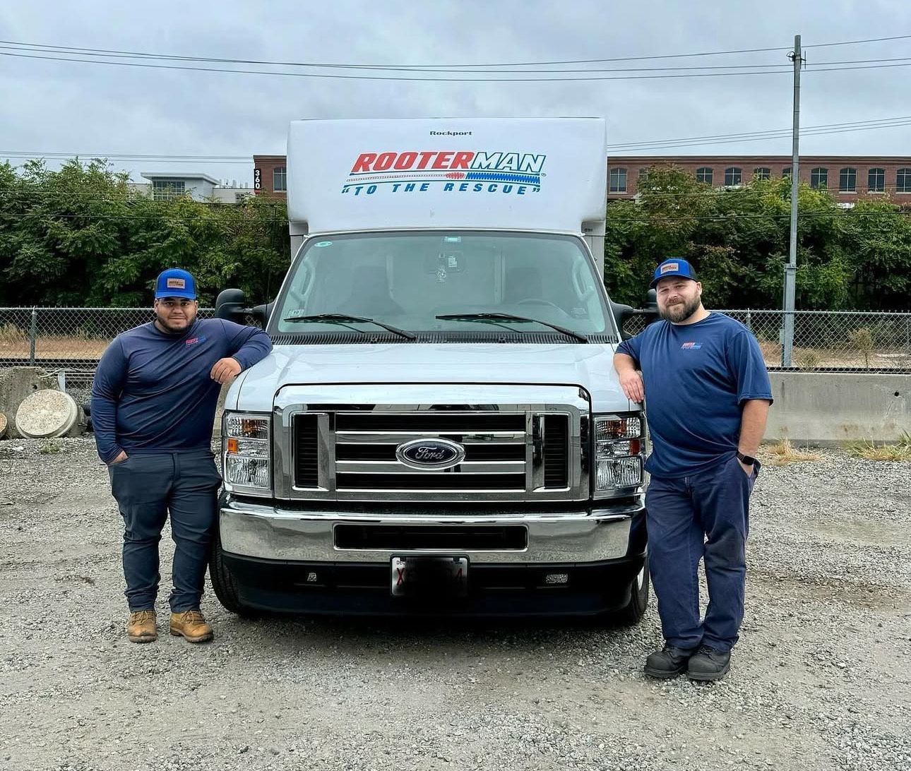 White vacuum truck on asphalt road, with a worker standing nearby.