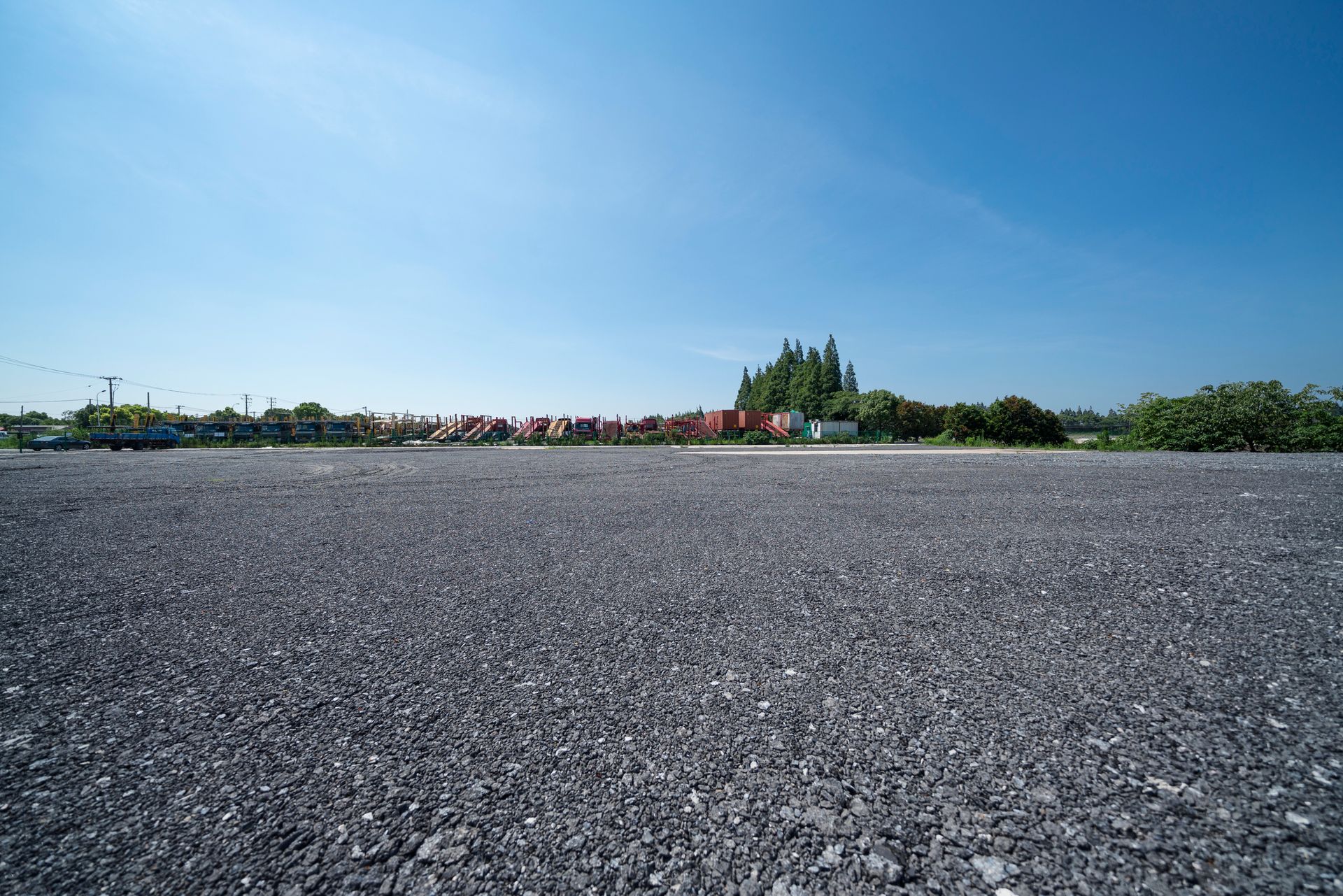A large empty asphalt road with trees in the background on a sunny day.