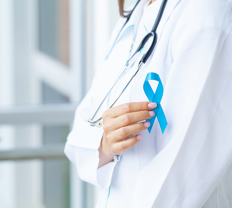 A doctor is holding a blue ribbon on her chest.
