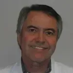 A man in a white lab coat is smiling for the camera.