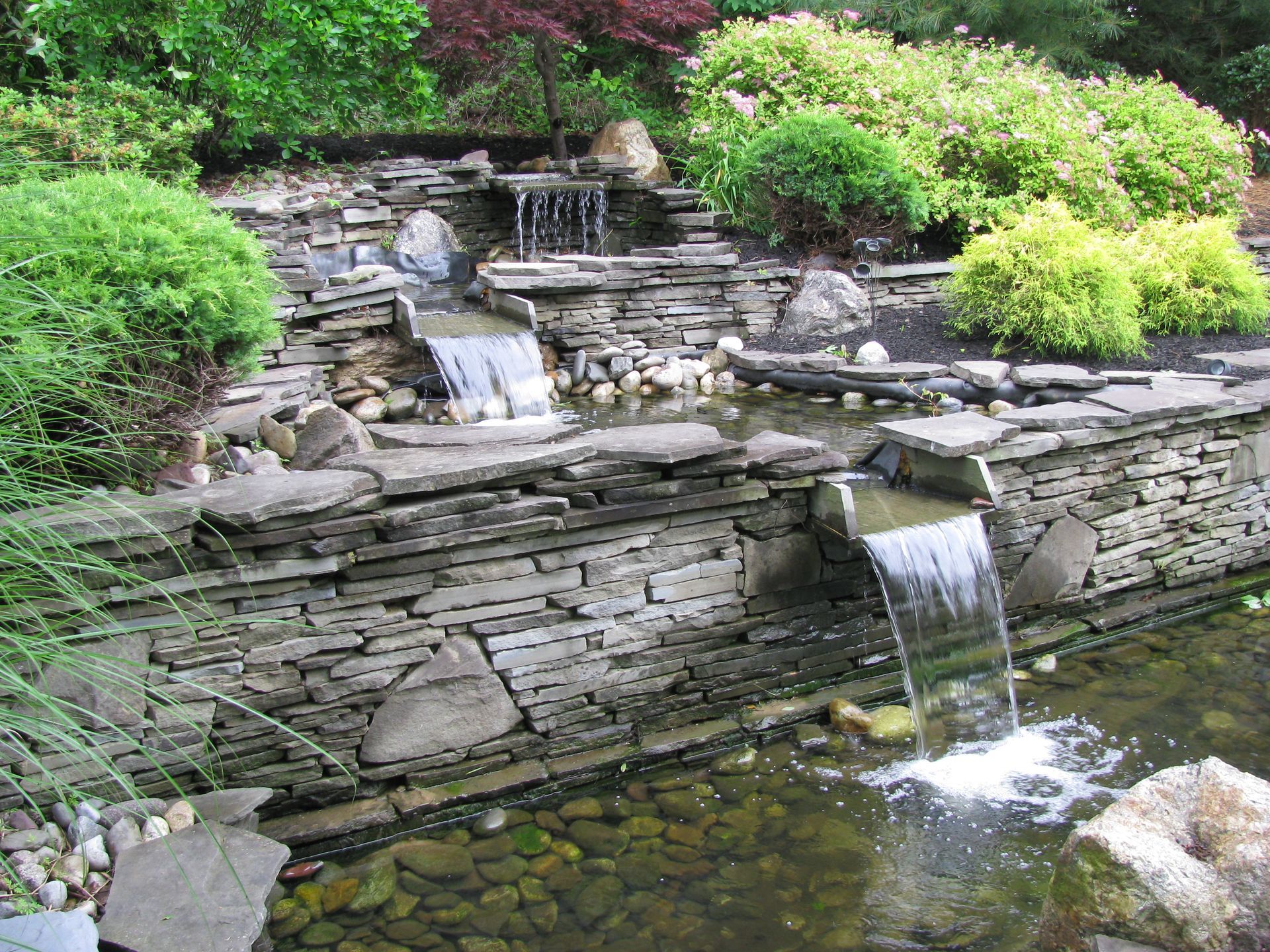 A Waterfall Is Surrounded By A Stone Wall — Columbus, NJ — G & G Landscaping Construction, Inc.