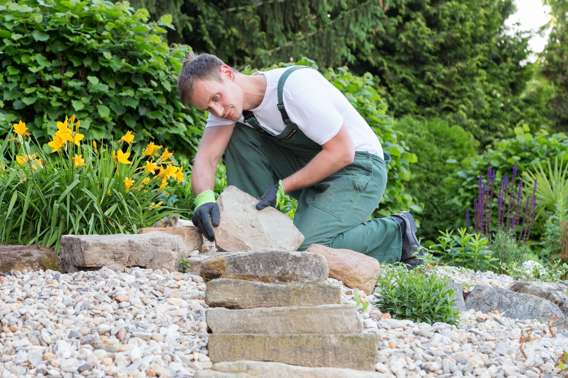 Residential landscaping contractors placing natural stone steps in a backyard landscape design. Residential landscaping contractors placing natural stone steps in a backyard landscape design.