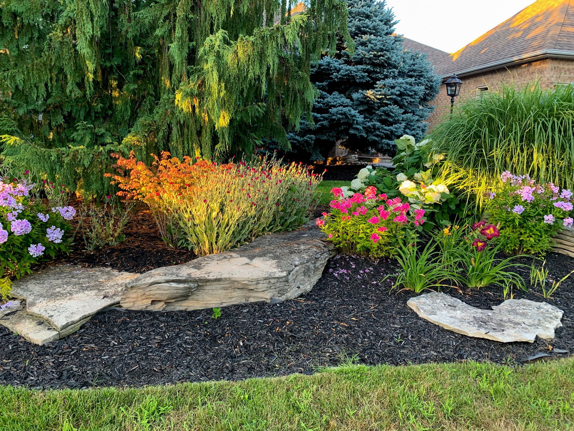 A Colourful garden with flowers, shrubs, and stone accent.