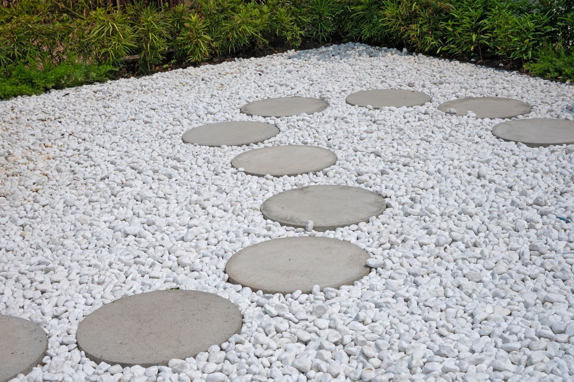 A walkway made of white gravel and stepping stones A walkway made of white gravel and stepping stones