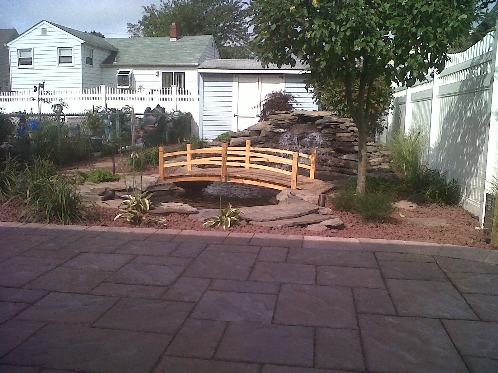 A Small Wooden Bridge Is In The Middle Of A Garden — Columbus, NJ — G & G Landscaping Construction, Inc.