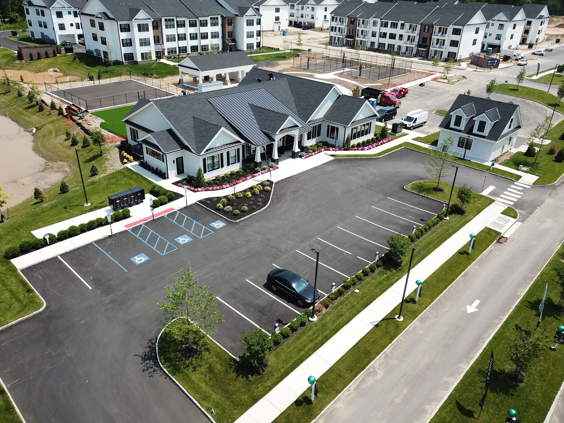 Aerial view of a parking lot and clubhouse next to apartment buildings under construction.