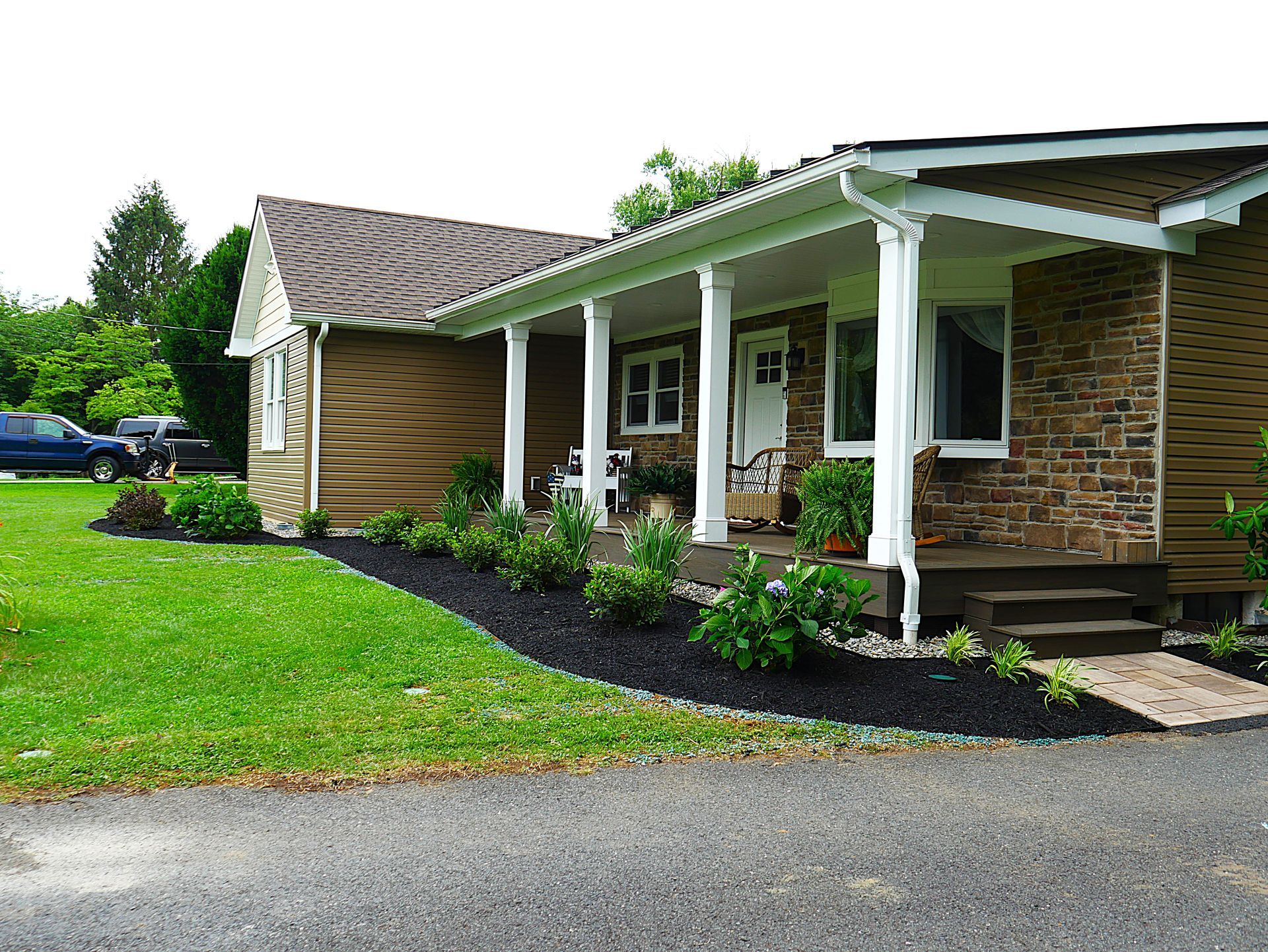 A house with a porch and a lawn in front of it.