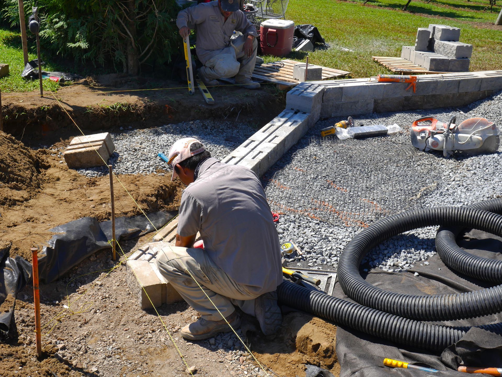Custom landscaping contractor building a stone retaining wall with precision leveling tools.