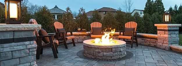 Outdoor stone patio with fire pit, surrounded by Adirondack chairs and decorative lighting. Outdoor stone patio with fire pit, surrounded by Adirondack chairs and decorative lighting.