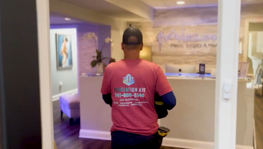 Person in a red shirt standing at a reception desk in a softly lit hallway
