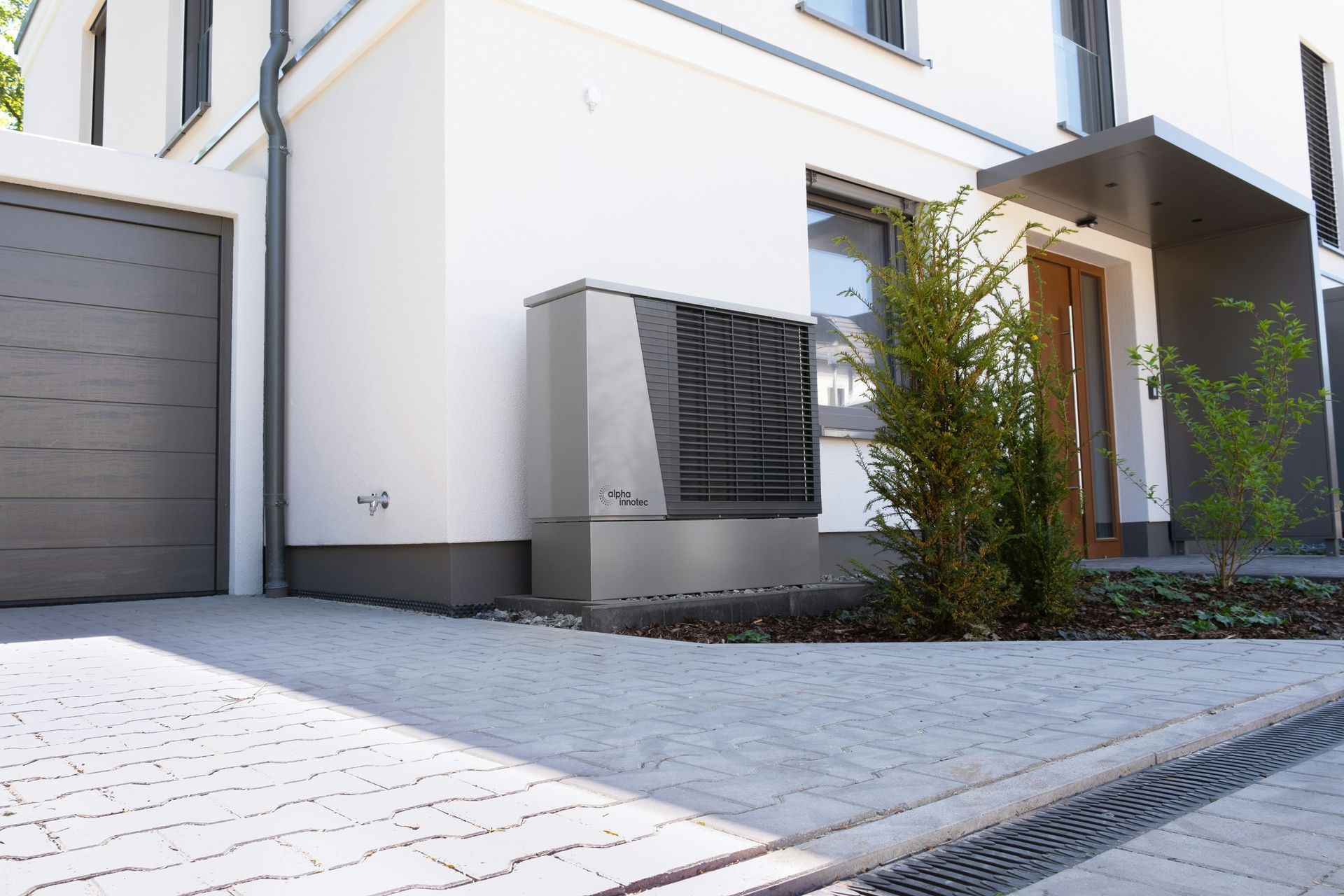 Modern white house exterior with gray garage, front entrance, and paved driveway.