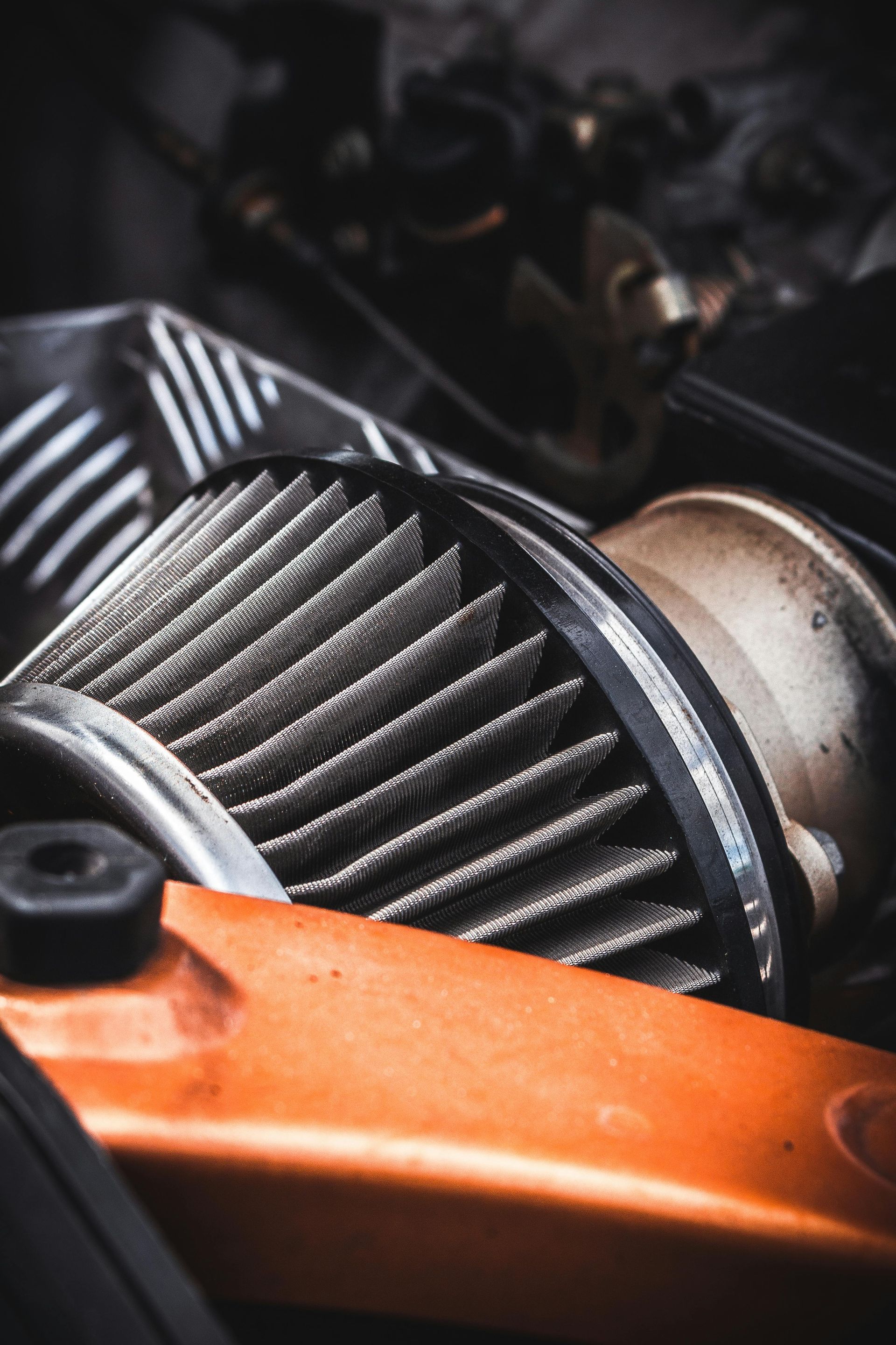 Close-up of a car engine turbocharger with orange piping and metallic fins