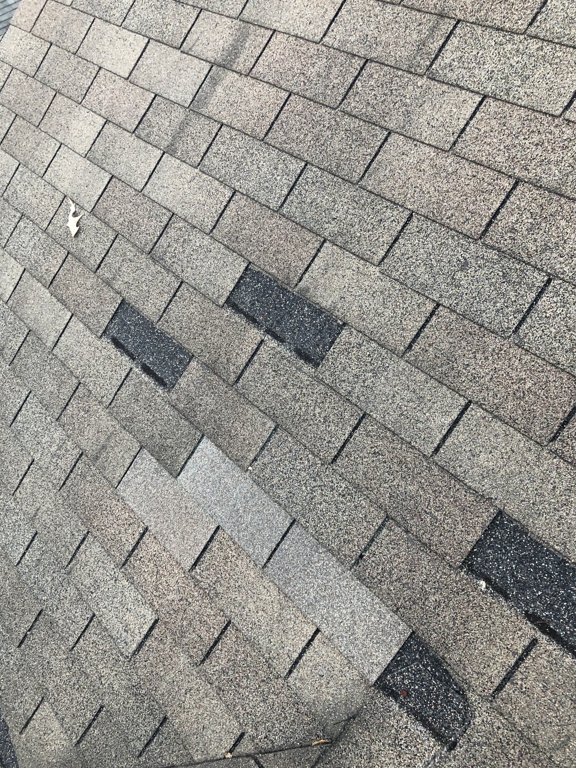 Image of wind-damaged shingles on residential roof. 