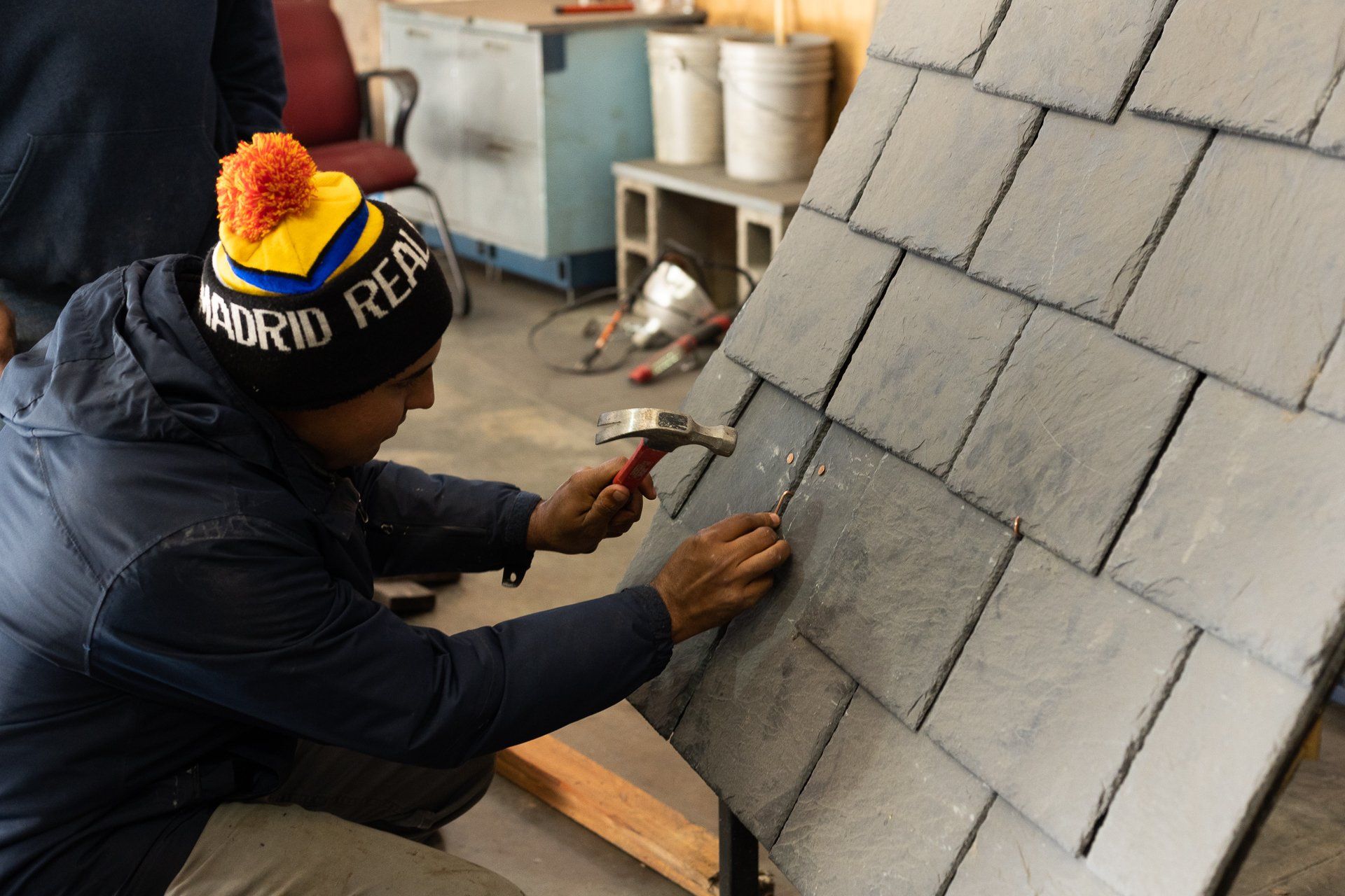 An image of RETEX's Julio Marin installing natural slate on a roof template during a team training event.
