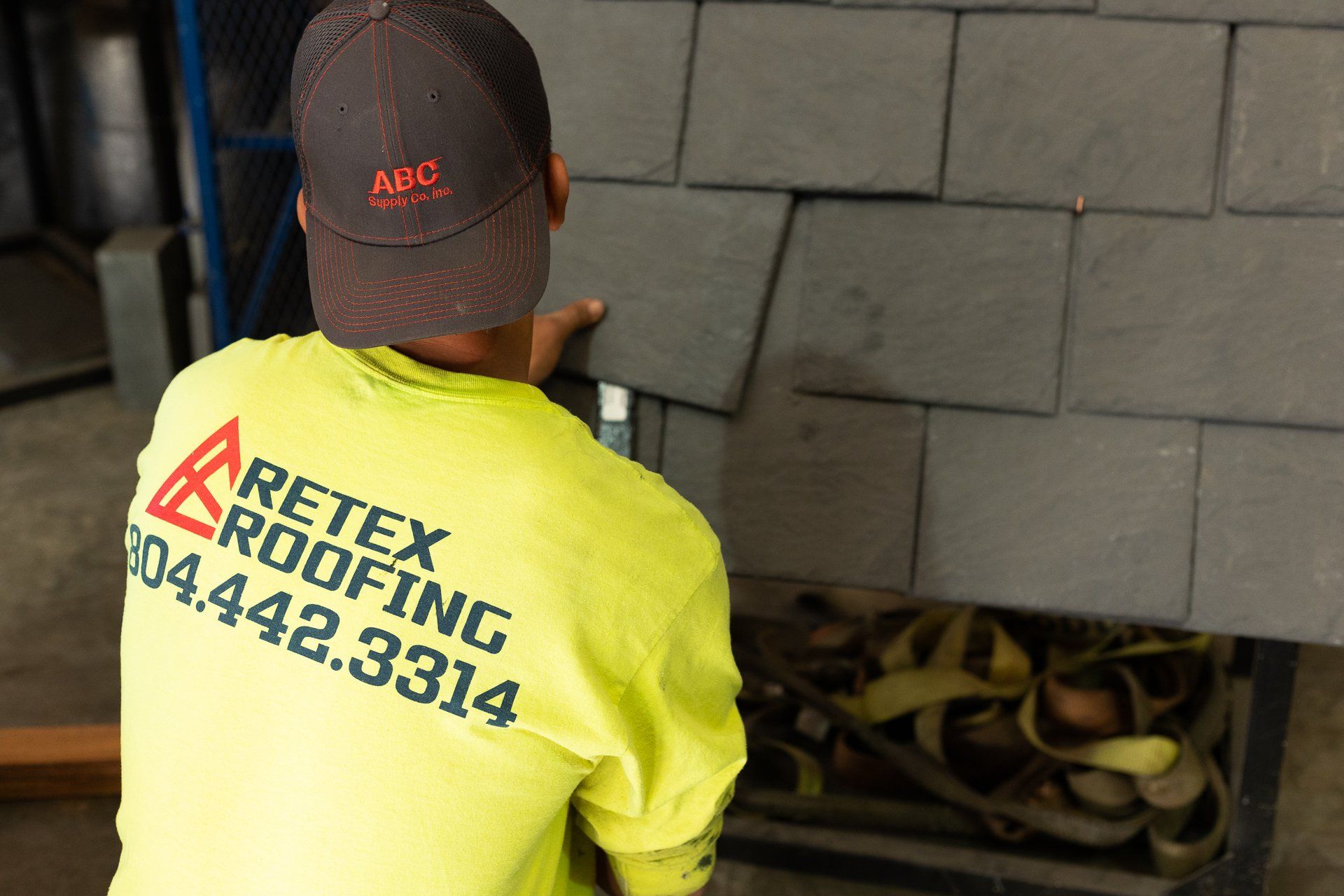 An image of RETEX's Bryan Rizo installing natural slate on a roof template during a team training event.