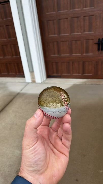 Image of a baseball, held in RETEX's Andy Connor's hand after he dislodged it from a downspout for a client.