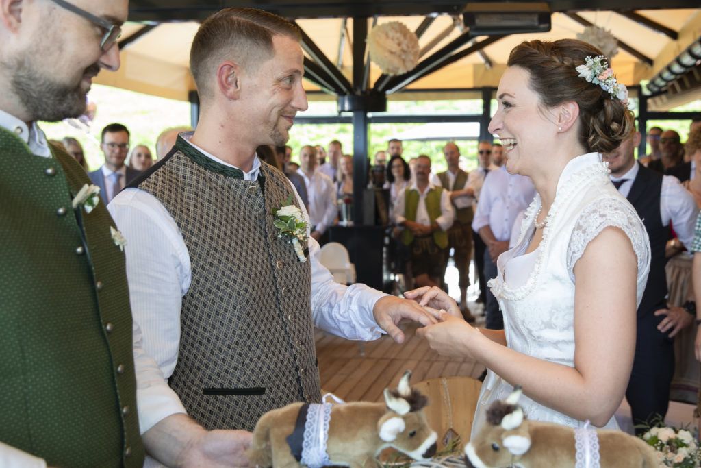 Ein Mann steckt einer Braut einen Ehering an den Finger.