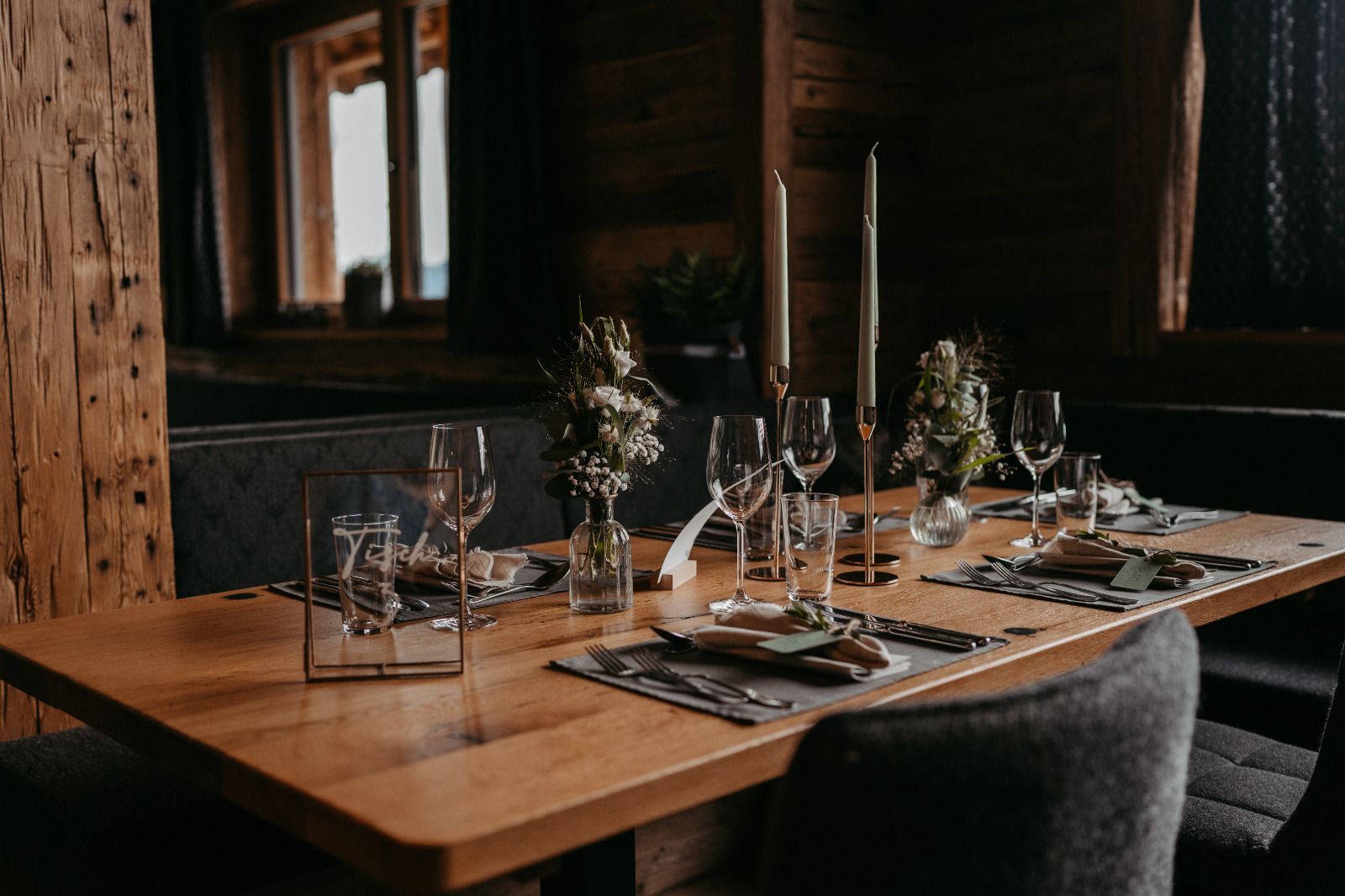 Ein Holztisch mit Tellern, Gläsern und Kerzen darauf.