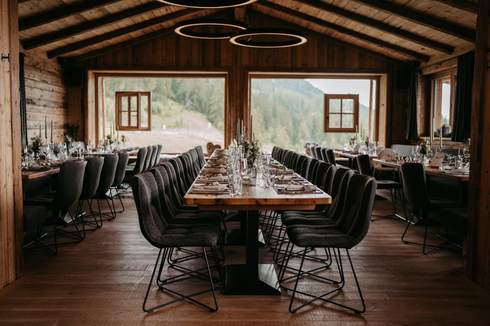 Ein langer Tisch und Stühle in einem Holzraum mit Blick auf die Berge.