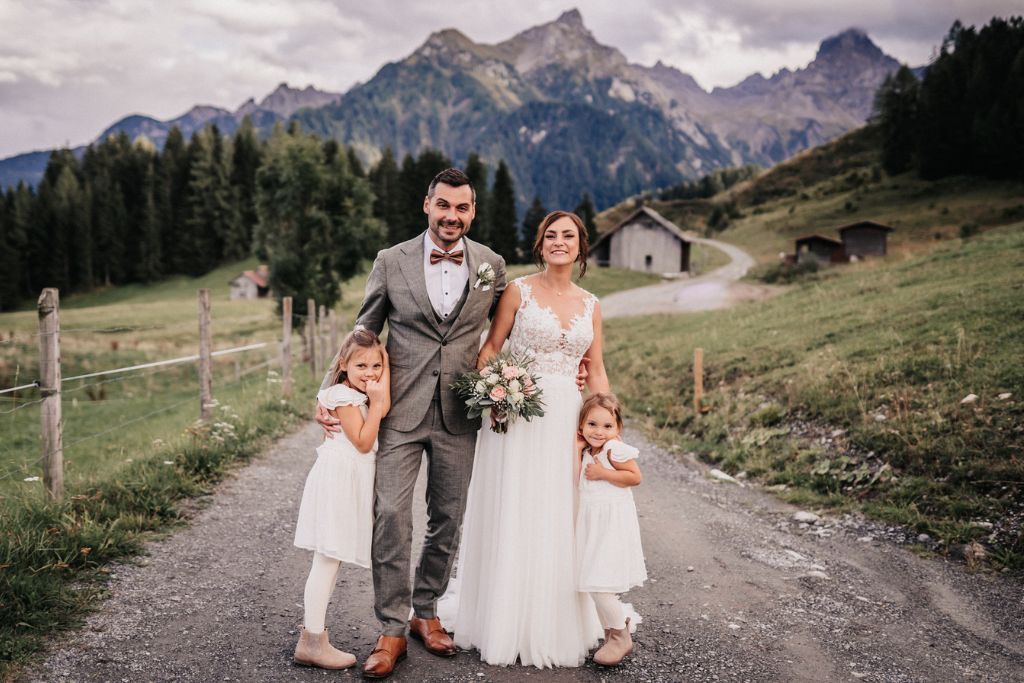 Braut und Bräutigam posieren mit ihren beiden Töchtern für ein Foto.