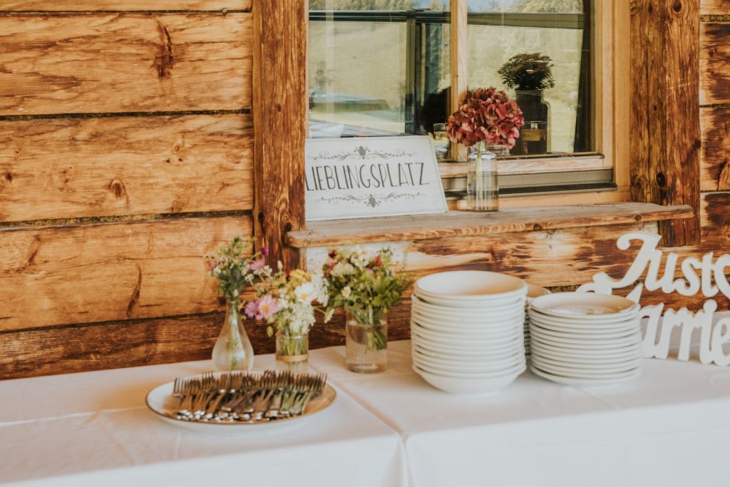 Ein Tisch mit Tellern und Blumen darauf vor einer Holzwand.