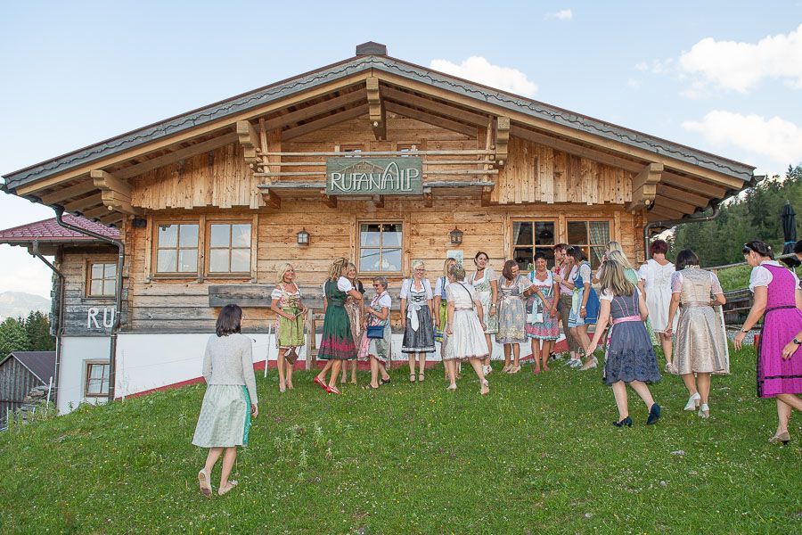 Eine Gruppe von Menschen steht vor einem Holzhaus.