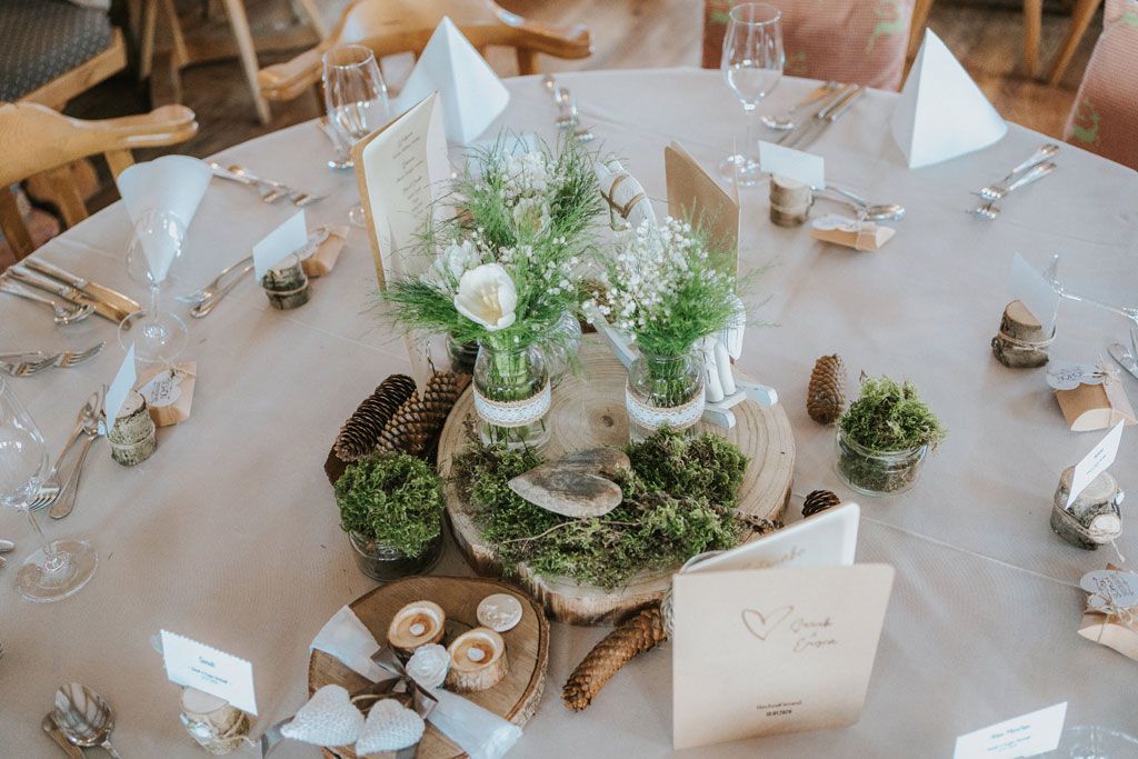 Ein für einen Hochzeitsempfang gedeckter Tisch mit einem hölzernen Tafelaufsatz.