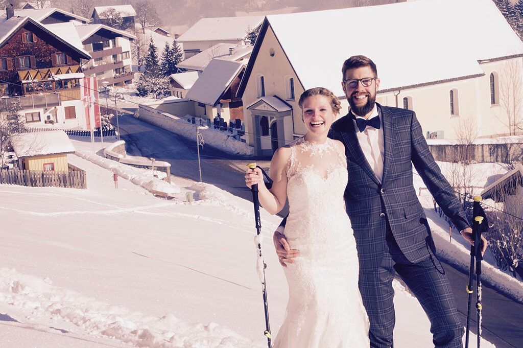 Eine Braut und ein Bräutigam posieren für ein Foto im Schnee.