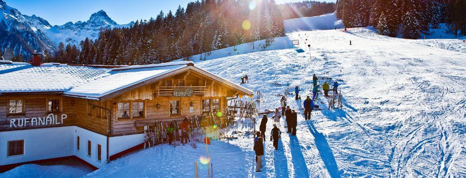 Eine Gruppe von Menschen läuft eine schneebedeckte Skipiste hinunter.