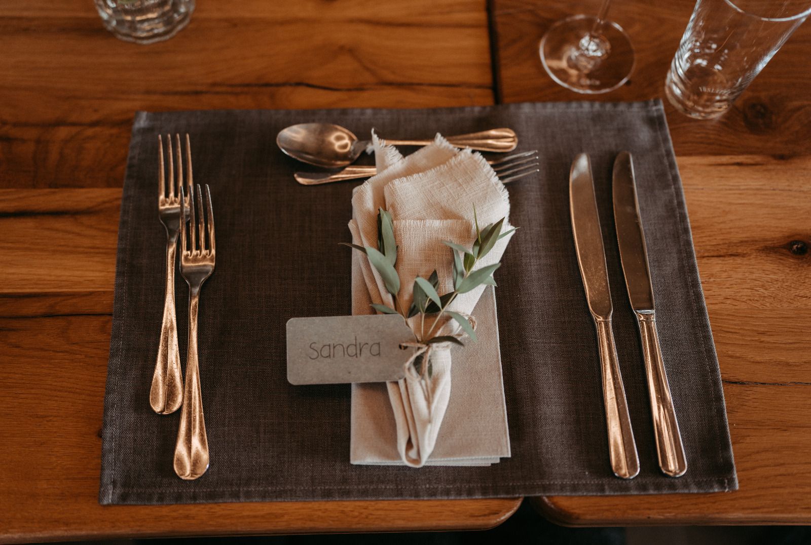 Ein Gedeck mit Besteck und einer Serviette auf einem Holztisch.