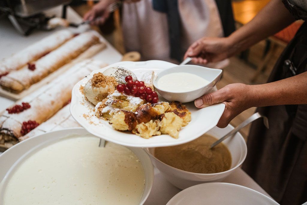 Eine Person hält einen Teller mit Essen auf einem Tisch.
